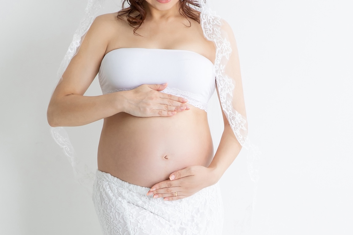 白い服を纏った妊婦さんの立ち姿のお写真
